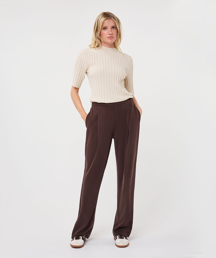 Woman modelling an ivory ribbed knit short-sleeve top with a high neckline and fitted silhouette, shown from the front.
