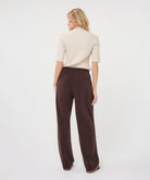 Woman modelling an ivory ribbed knit short-sleeve top with a high neckline and fitted silhouette, shown from the back.