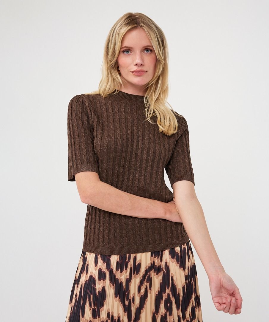 Woman modelling a brown ribbed knit short-sleeve top with a high neckline and fitted silhouette, paired with a printed skirt.