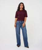 woman wearing a burgundy ribbed knit top with subtle sparkle detailing and blue wide-leg jeans