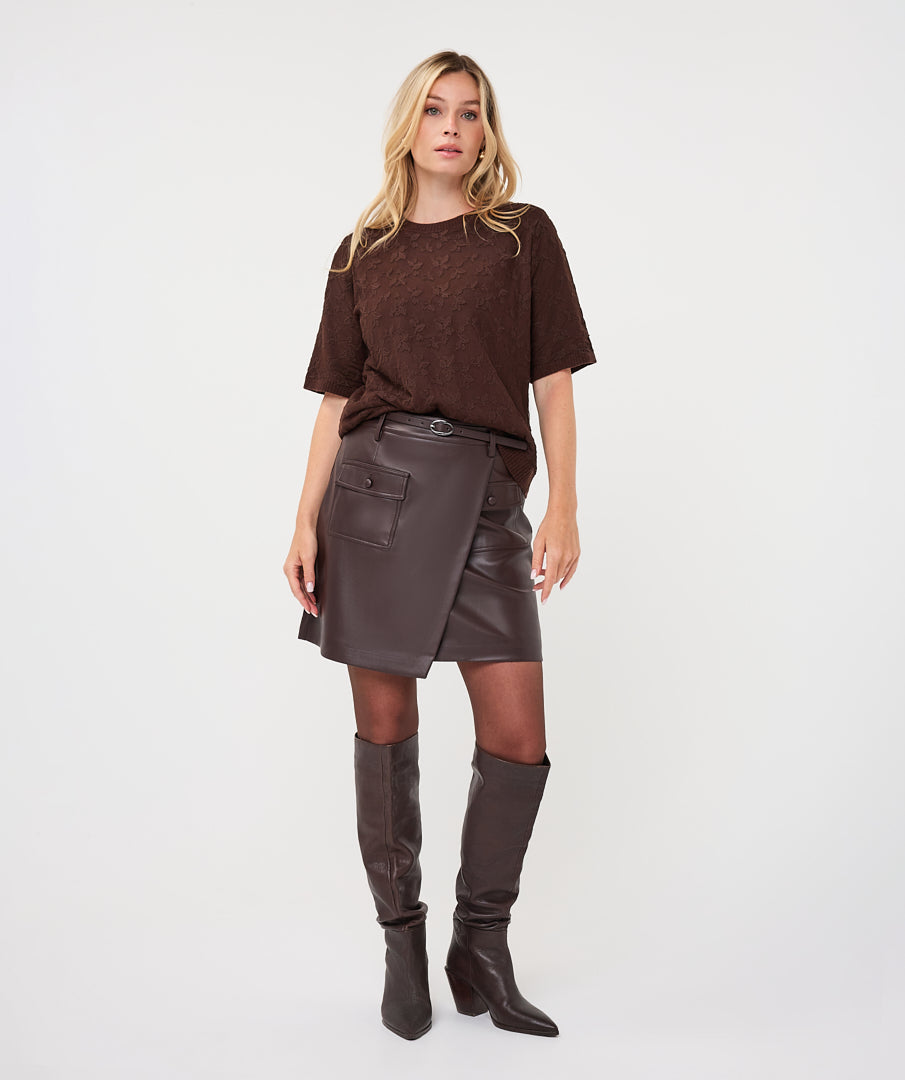Woman wearing the brown Rosalie Lace Top with a leather-look wrap skirt and knee-high boots, front view.