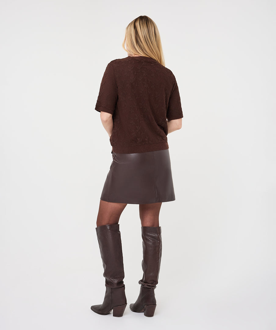 Woman wearing the brown Rosalie Lace Top with a leather-look wrap skirt and knee-high boots
