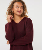 Woman wearing a burgundy V-neck sweater with long sleeves and a relaxed fit