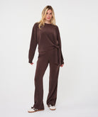 Full-length back view of a woman wearing the chocolate brown Sloane Side-Tie Sweater with matching relaxed-fit trousers, highlighting the coordinated look and fluid drape.