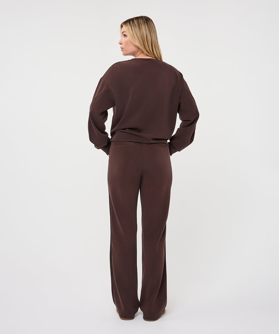 Full-length back view of a woman wearing the chocolate brown Sloane Side-Tie Sweater with matching relaxed-fit trousers, highlighting the coordinated look and fluid drape.
