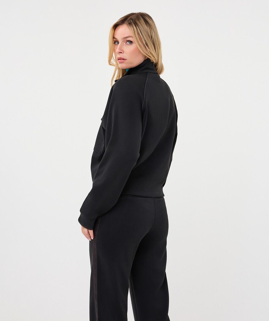 Woman wearing a black utility jacket with a stand collar and flap chest pockets 