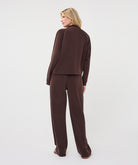Full-length view of a woman wearing a chocolate brown utility jacket with matching wide-leg trouser seen from the back.