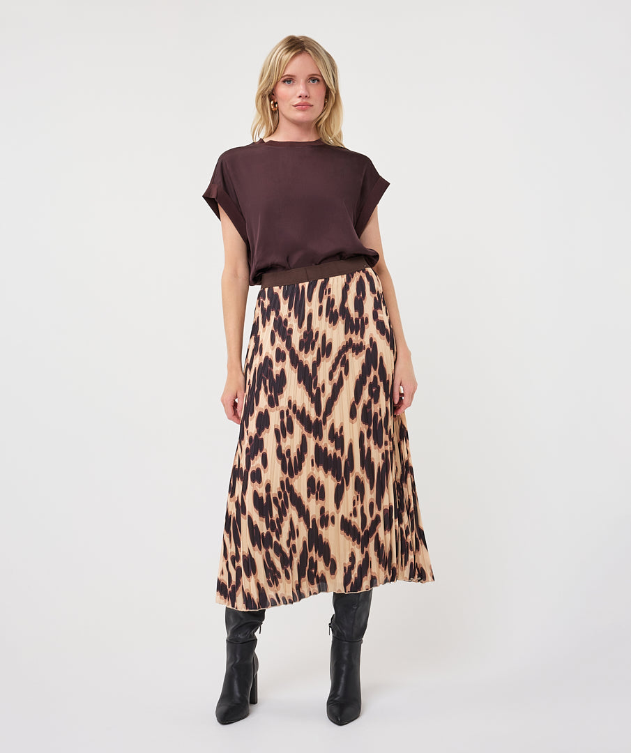 Woman wearing a dark brown satin roll-sleeve top with a printed midi skirt and knee-high boots, front view.