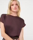 Woman wearing a dark brown satin roll-sleeve top
