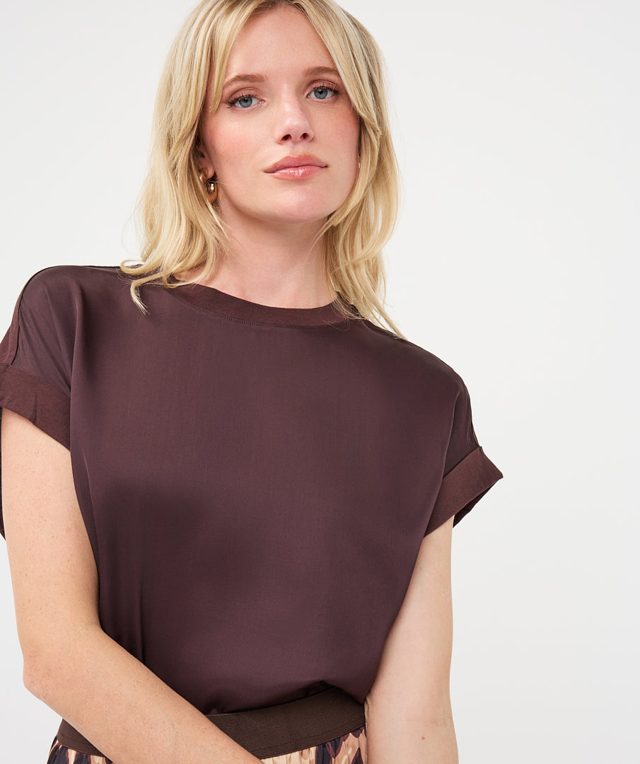 Woman wearing a dark brown satin roll-sleeve top