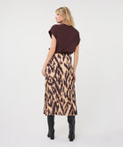 Woman wearing a dark brown satin roll-sleeve top with a printed midi skirt and knee-high boots