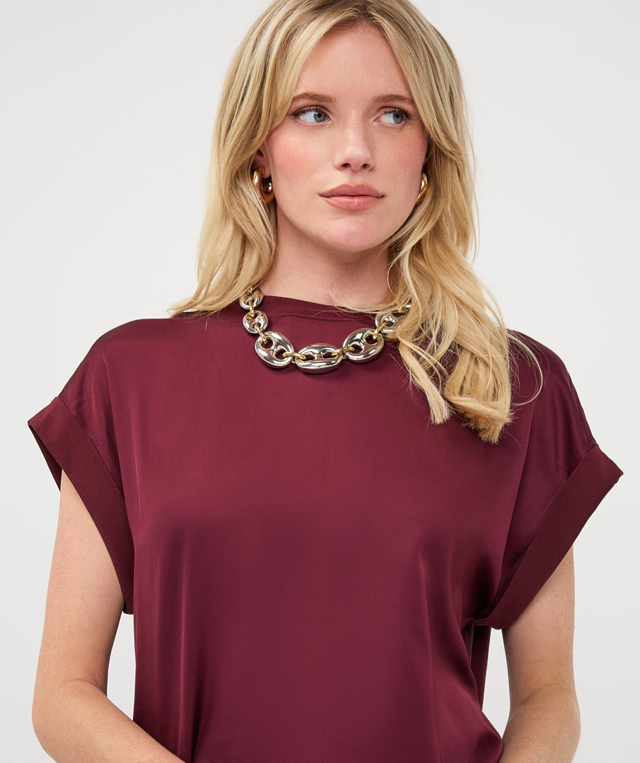 Woman wearing a burgundy satin roll-sleeve top