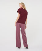 Woman wearing a burgundy satin roll-sleeve top with mauve pinstripe wide-leg trousers