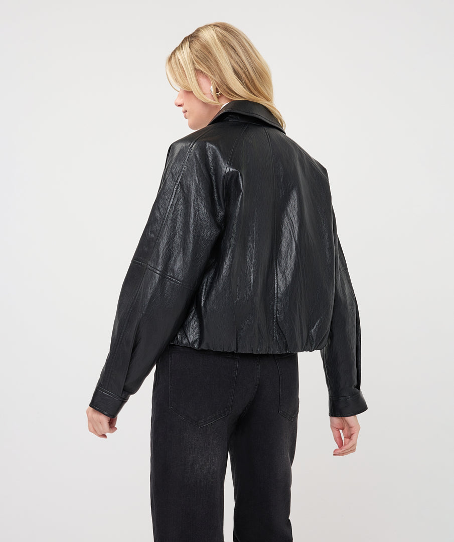 Woman wearing a dark gray cropped faux leather jacket with a collared neckline and button-front closure