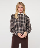 Model wearing a brown and taupe plaid short blouse with a white pointed collar and long sleeves, shown from the front.