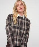Model wearing a brown and taupe plaid short blouse with a white pointed collar and long sleeves, shown from the front.