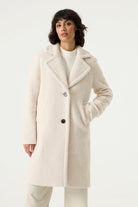 Woman wearing a cream Lennox Textured Coat with notched lapels, button front and side pockets.