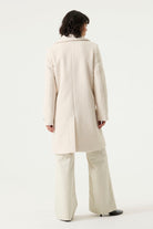 Woman wearing a cream Lennox Textured Coat with notched lapels, button front and side pockets.