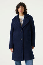 Woman wearing a navy Lennox Textured Coat with notched lapels, button front and longline silhouette.