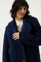 Woman wearing a navy Lennox Textured Coat with notched lapels, button front and longline silhouette.