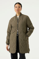 Woman modelling a longline olive green quilted jacket with a ribbed collar and cuffs, full front zip closure, side pockets, and rounded hem.