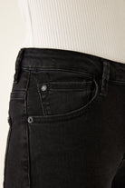 Close-up of black jeans with a beige background