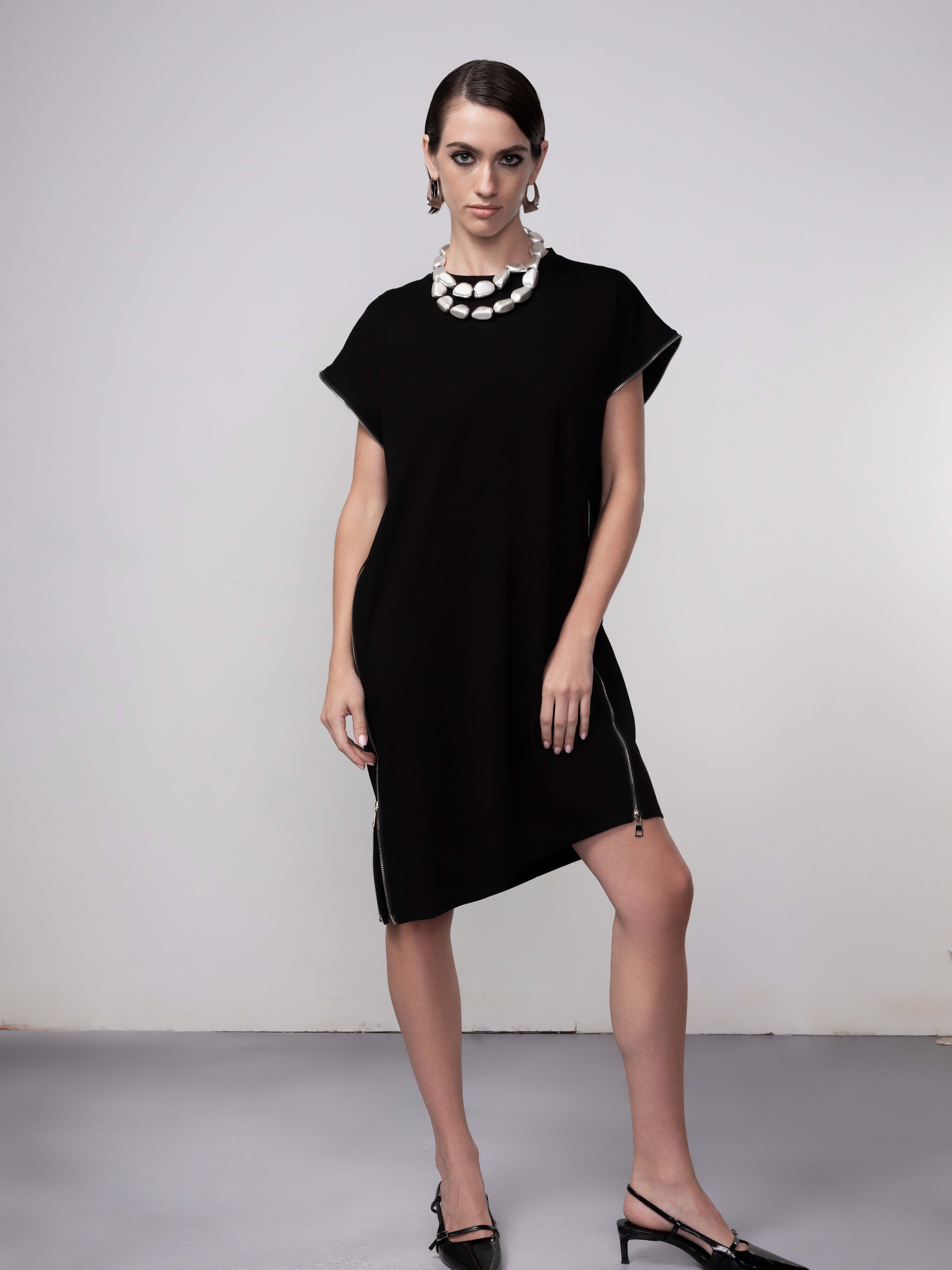 Model wearing a black tunic dress with cap sleeves and side zip detail, front view