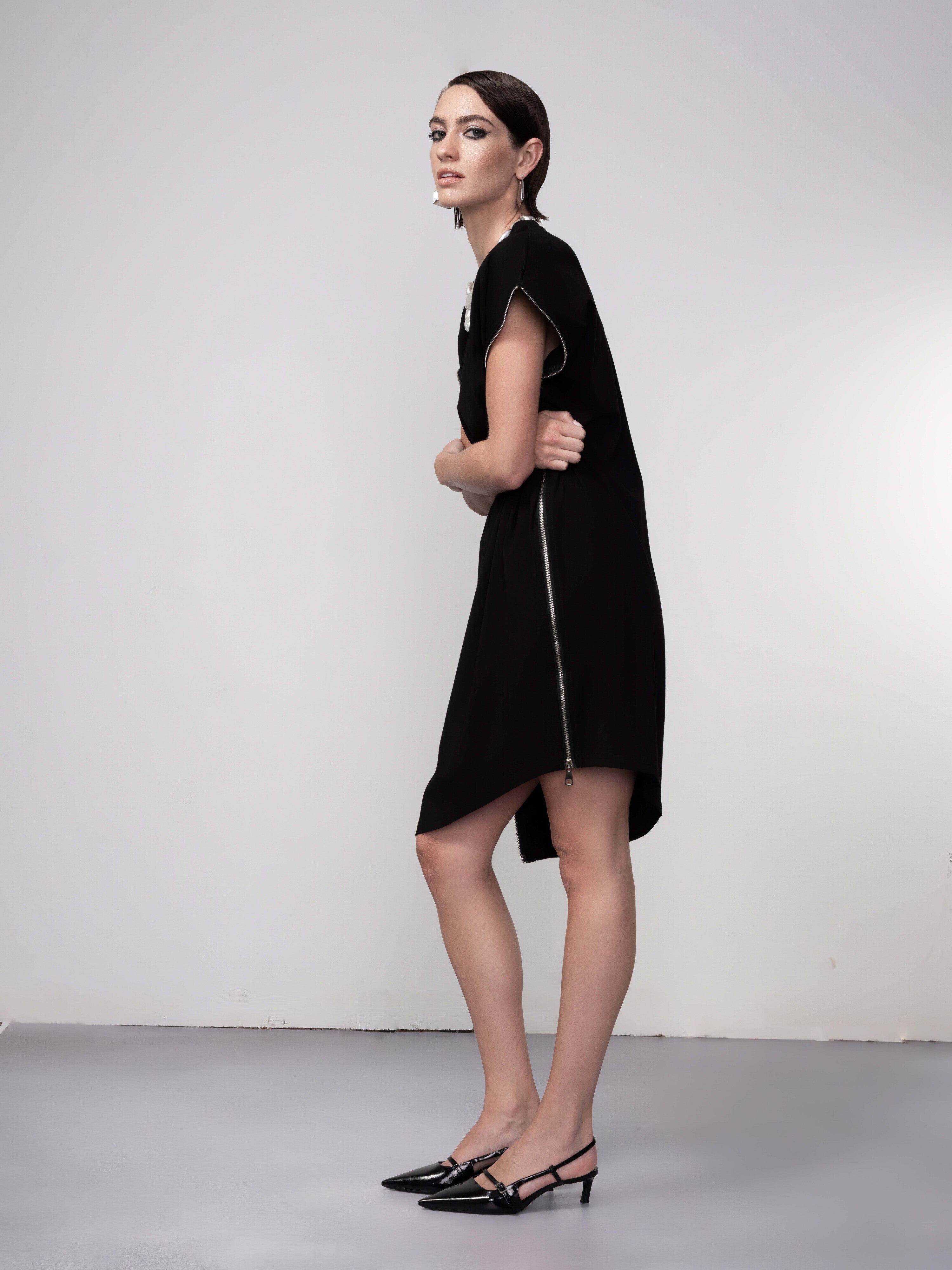 Side view of black tunic dress with cap sleeves and asymmetrical hem detail