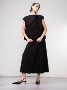 Woman wearing a black cocoon-style pullover top paired with a matching midi skirt and pointed slingback heels, shown in a full-length studio pose.