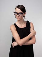 Woman wearing a black sleeveless midi dress with gathered neckline and tie-shoulder detail