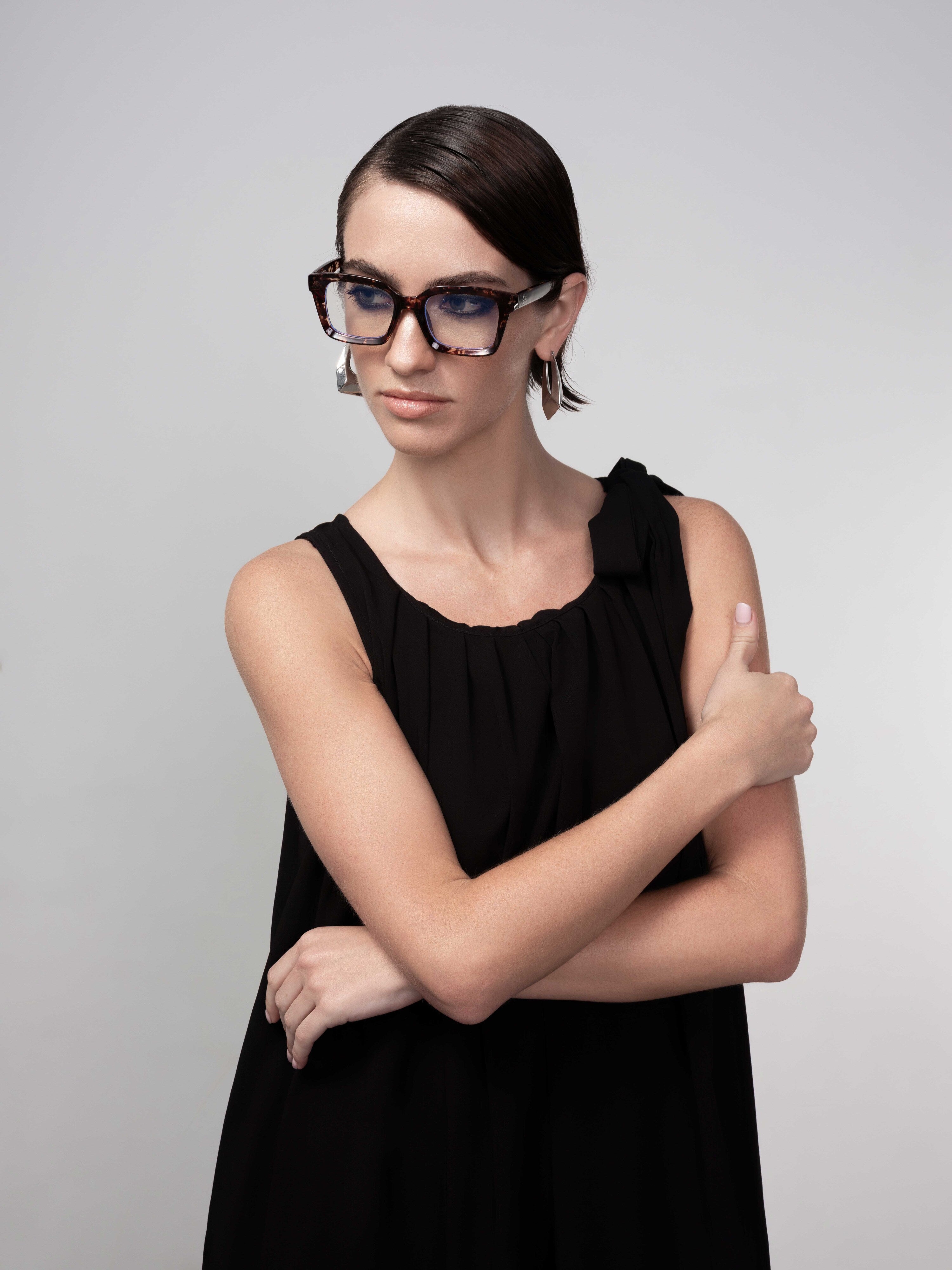 Woman wearing a black sleeveless midi dress with gathered neckline and tie-shoulder detail