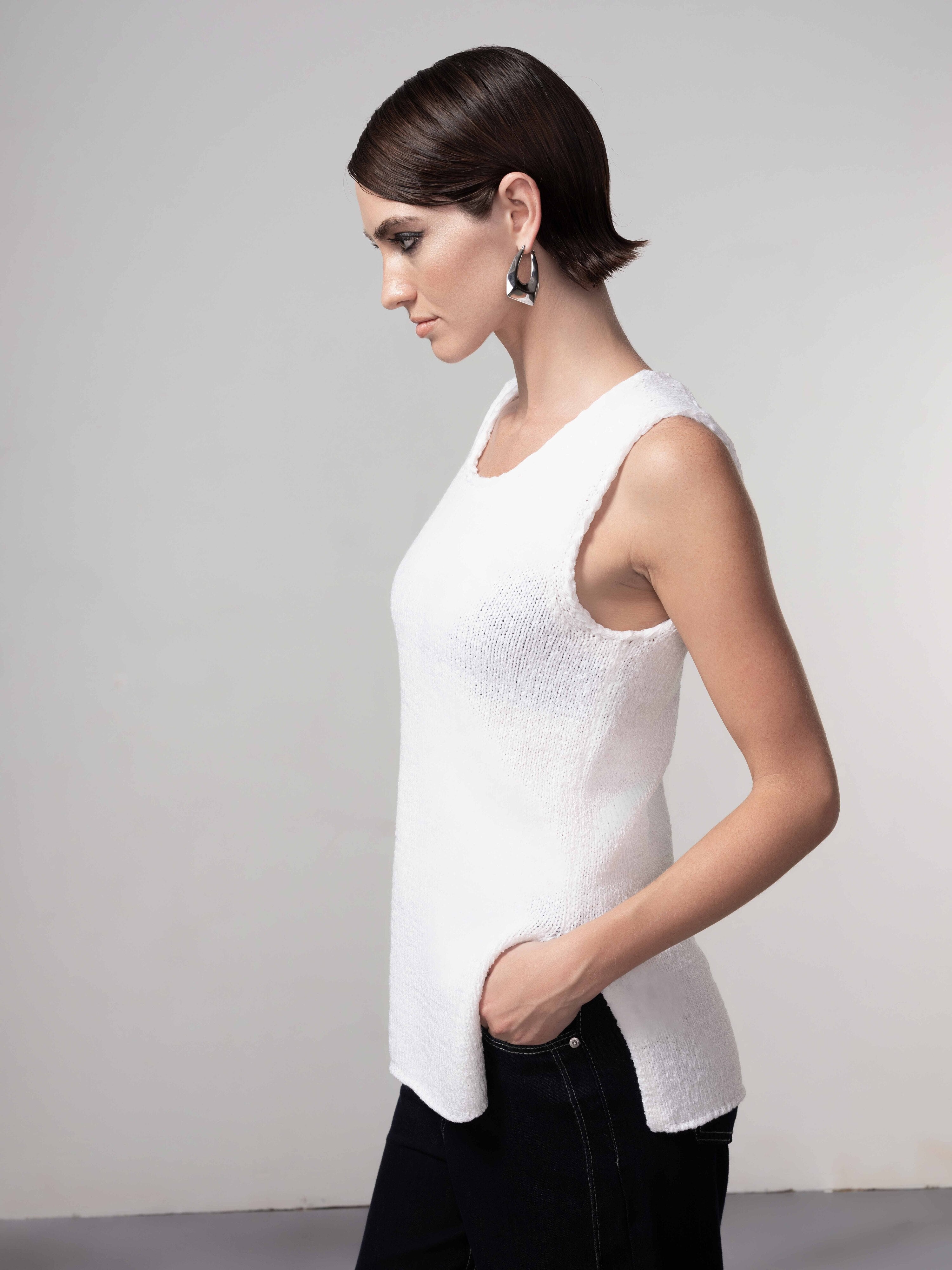 woman wearing a white sleeveless knit shell top with wide-leg dark jeans