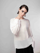 Woman wearing a soft white lightweight knit sweater styled with a black midi skirt