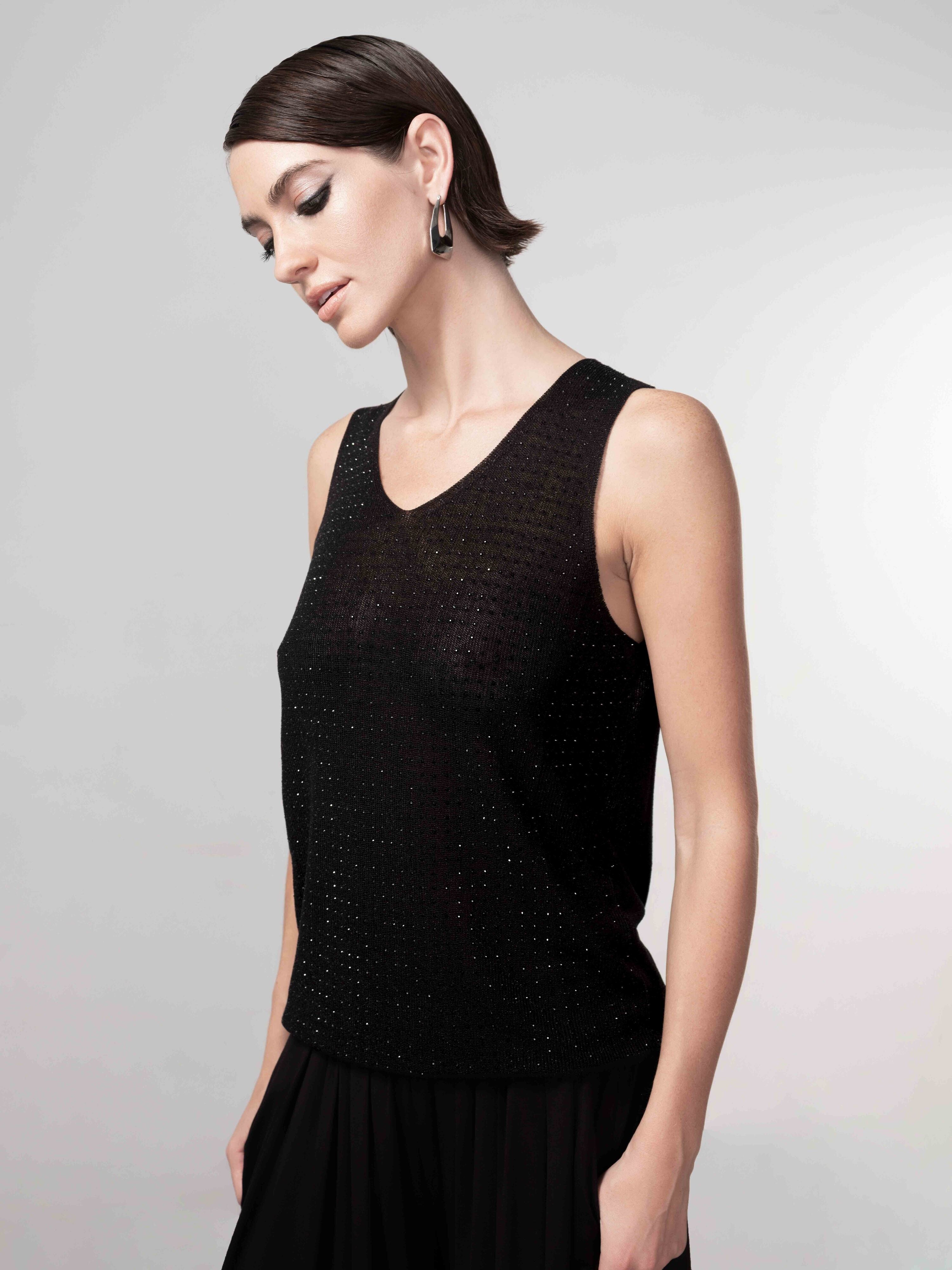 Close-up of a black sleeveless fine knit tank top on a model, highlighting the subtle textured fabric and classic crew neckline.