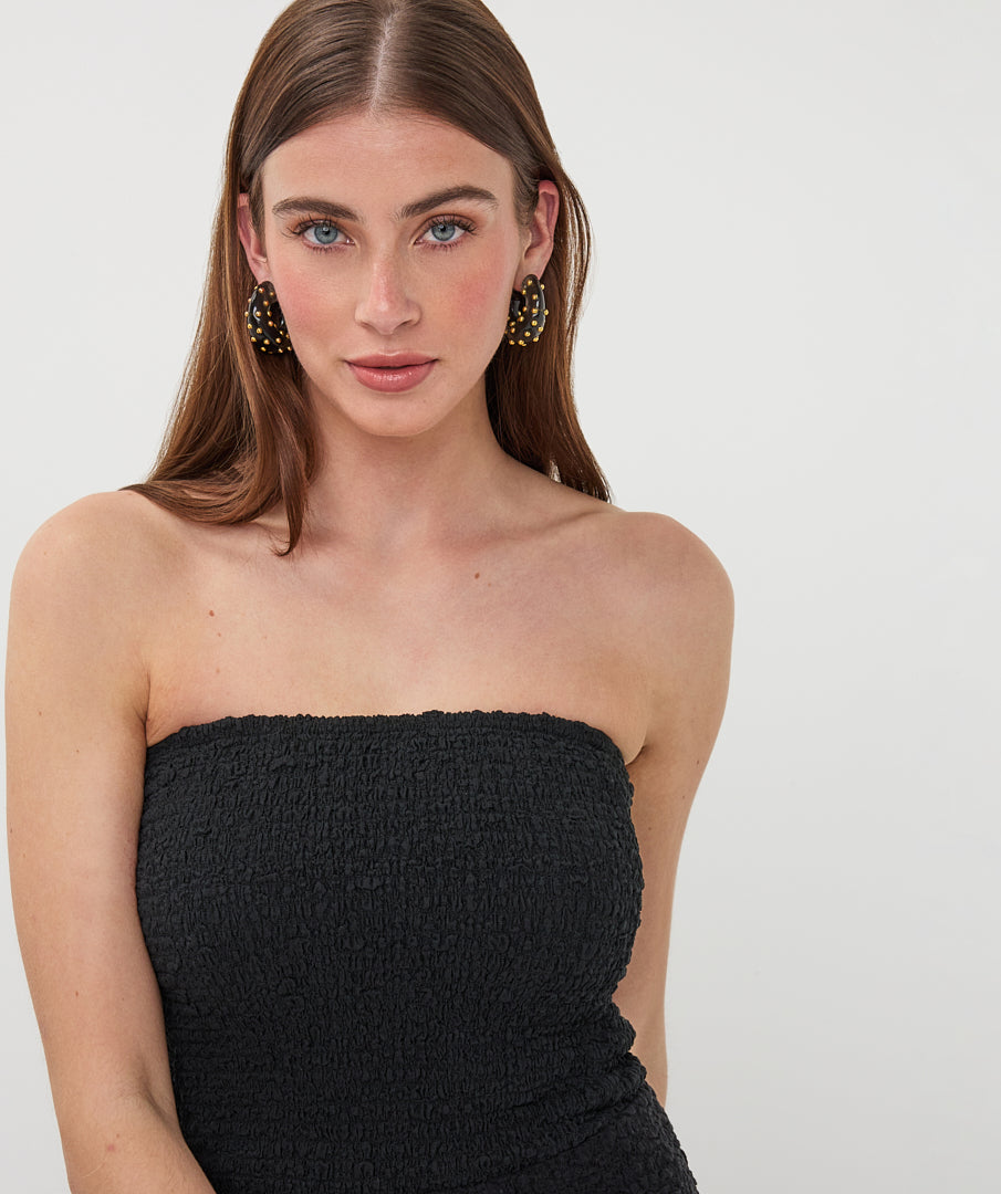 Close-up of black strapless textured tube top with a straight neckline and softly gathered, stretch fabric.