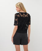 black short sleeve crochet cardigan with button-up closure and intricate open-stitch design, styled with matching shorts