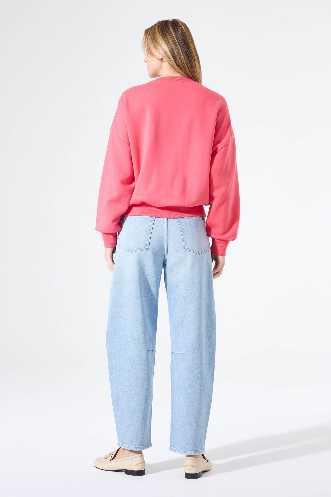 Woman wearing a relaxed-fit crewneck sweatshirt with ribbed hem and cuffs, paired with wide-leg jeans and loafers, shown from the back.