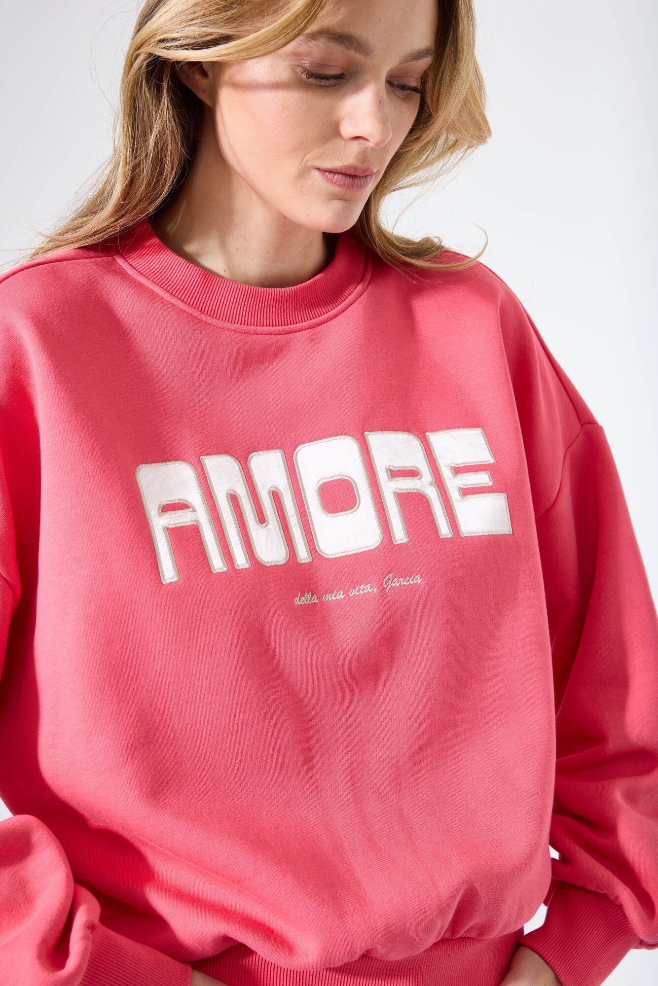 Relaxed-fit crewneck sweatshirt with long sleeves, ribbed trim, and “Amore” graphic lettering on the front.