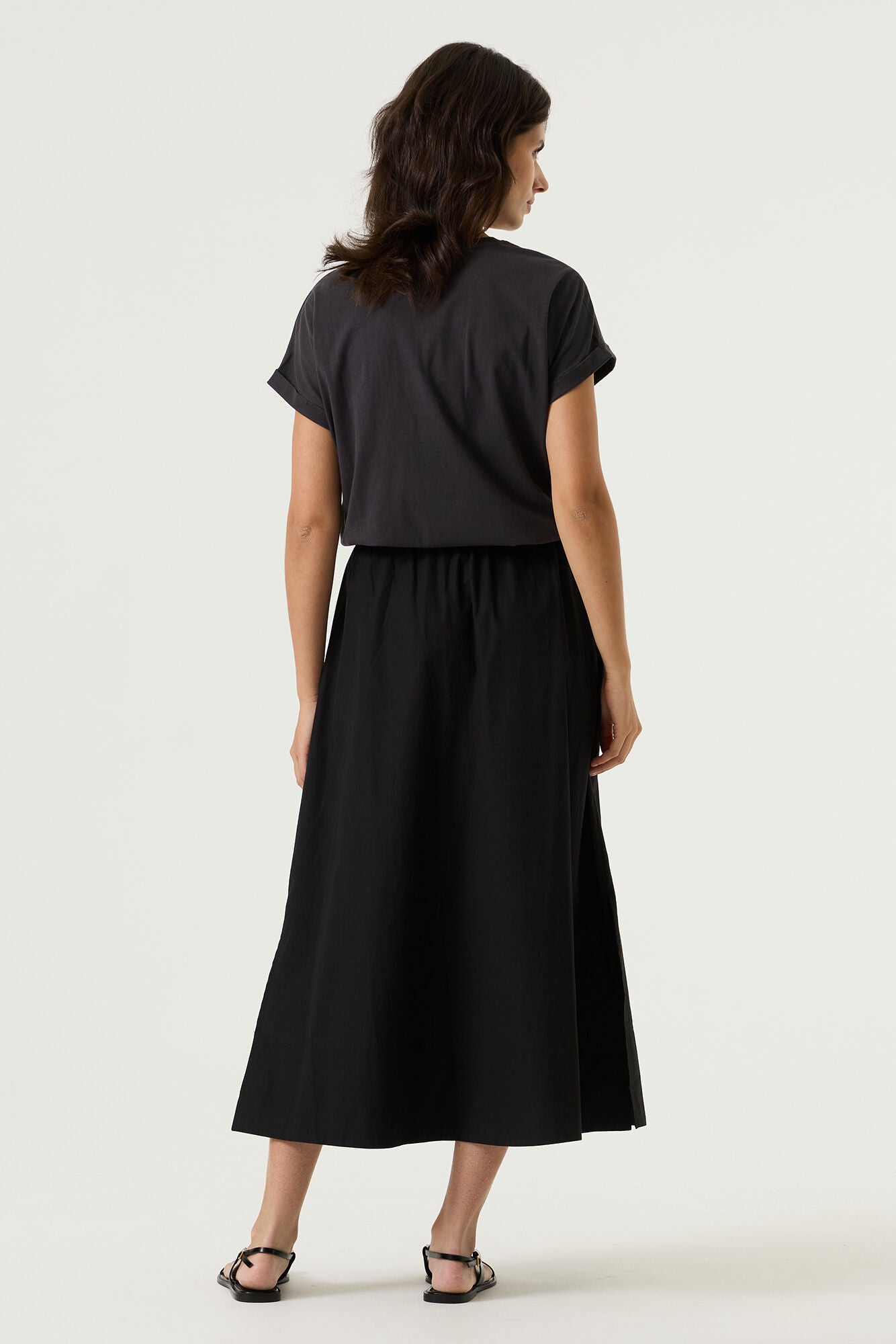 Woman wearing a charcoal relaxed fit graphic tee with “Sole Amalfi” text in light beige, styled with black skirt. 