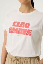Woman wearing a white relaxed fit graphic tee with “Ciao Amore” text in pink, paired with beige wide-leg drawstring pants