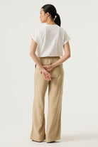 Woman wearing a white relaxed fit graphic tee with “Ciao Amore” text in pink, paired with beige wide-leg drawstring pants and flat sandals