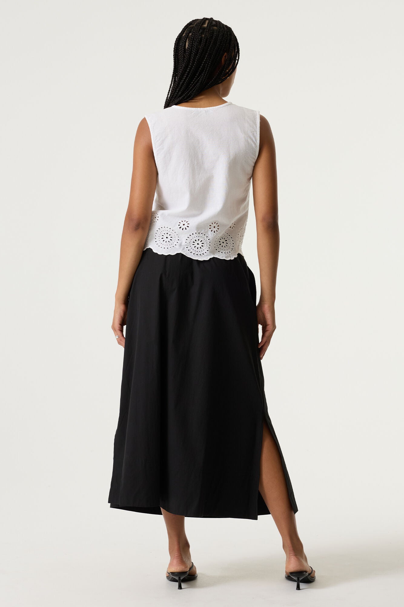 Women's white sleeveless cotton-linen blouse with eyelet embroidered scalloped hem. Shown from the back, highlighting the clean silhouette and relaxed fit.