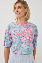 Woman wearing a floral patterned blouse against a plain background