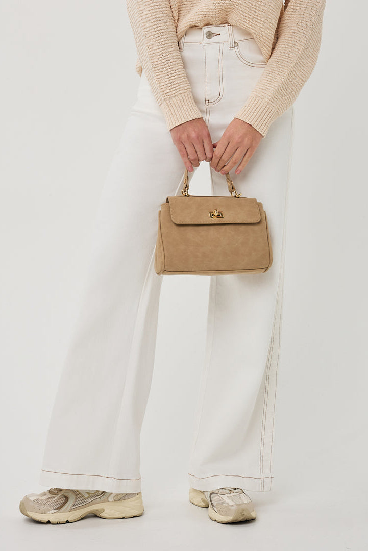 Person holding a beige handbag against a plain background