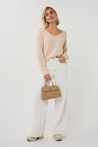 Woman holding a beige handbag against a white background