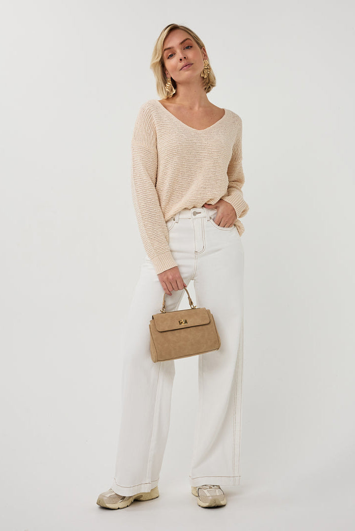 Woman holding a beige handbag against a white background
