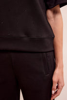Close-up of a person wearing a black outfit with a beige background