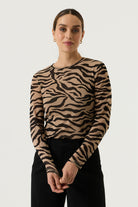 Back view of a woman wearing a tan and black zebra-print long-sleeve top with black wide-leg trousers