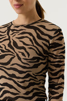 Close-up of a woman wearing a tan and black zebra-print long-sleeve top.