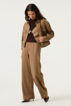Woman wearing the Aspen cropped utility jacket in brown with snap-button closure, flap chest pockets and long sleeves.